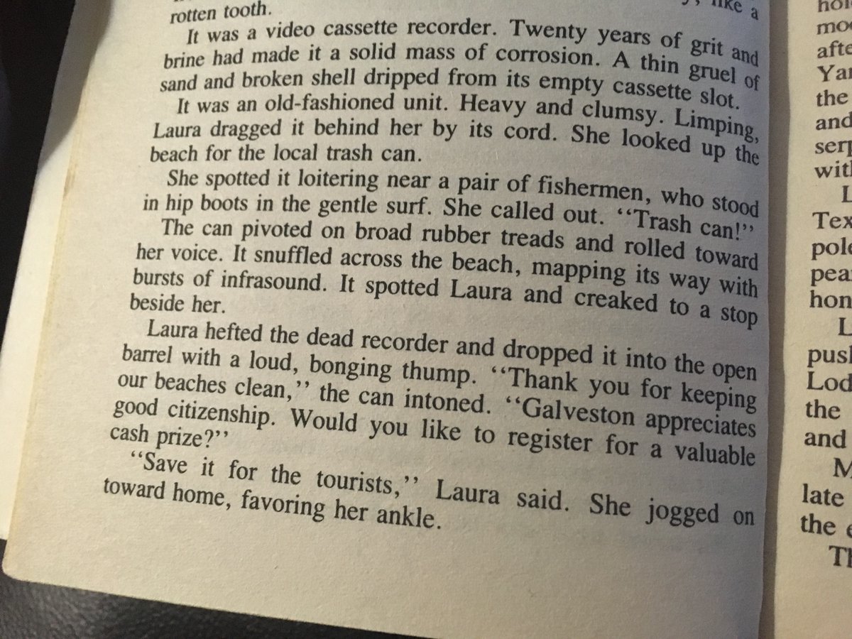 Photo of a page of the previous novel. It reads "It was a video casette recorder. Twenty years of grit and brine had made it a solid mass of corrosion. A thin gruel of sand and broken shell dropped from its empty casette slot.
"It was an old-fashioned unit. Heavy and clumsy. Limping, Laura dragged it behind her by its cord. She looked up the beach for the local trash can.
"She spotted it loitering near a pair of firemen, who stood in hip boots in the gentle surf. She called out, 'Trash can!'
"The can pivoted on broad rubber treads and rolled toward her voice. It snuffled across the beach, mapping its way with bursts of infrasound. It spotted Laura and creaked to a stop behind her.
"Laura hefted the dead recorder and dropped it into the open barrel with a loud, bonging thump. 'Thank you for keeping our beaches clean," the can intoned. 'Galveston appreciates good citizenship. Would you like to register for a valuable cash prize?'
"'Save it for the tourists,' Laura said. She jogged toward home, favoring her ankle."