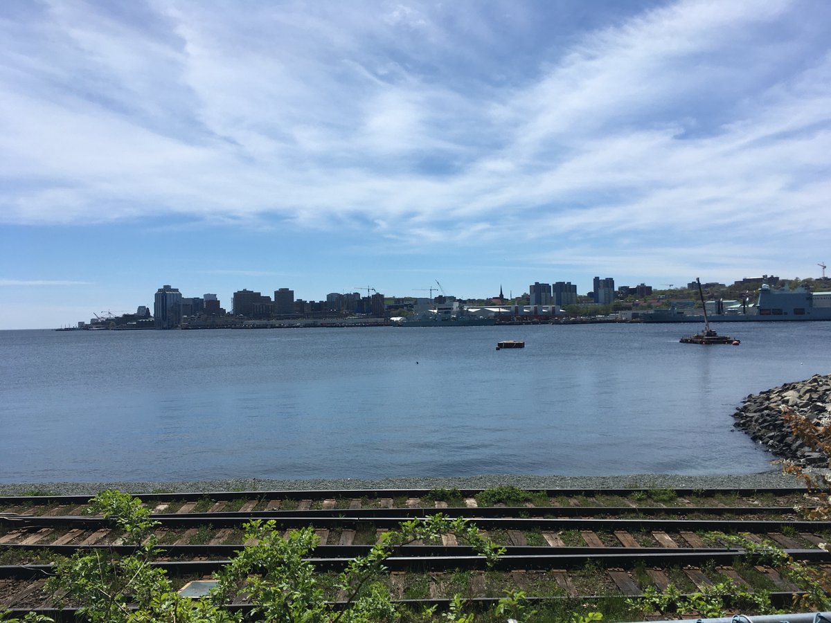 View of Halifax from across the harbor on a sunny day. Railway tracks lay between the viewer and the water.